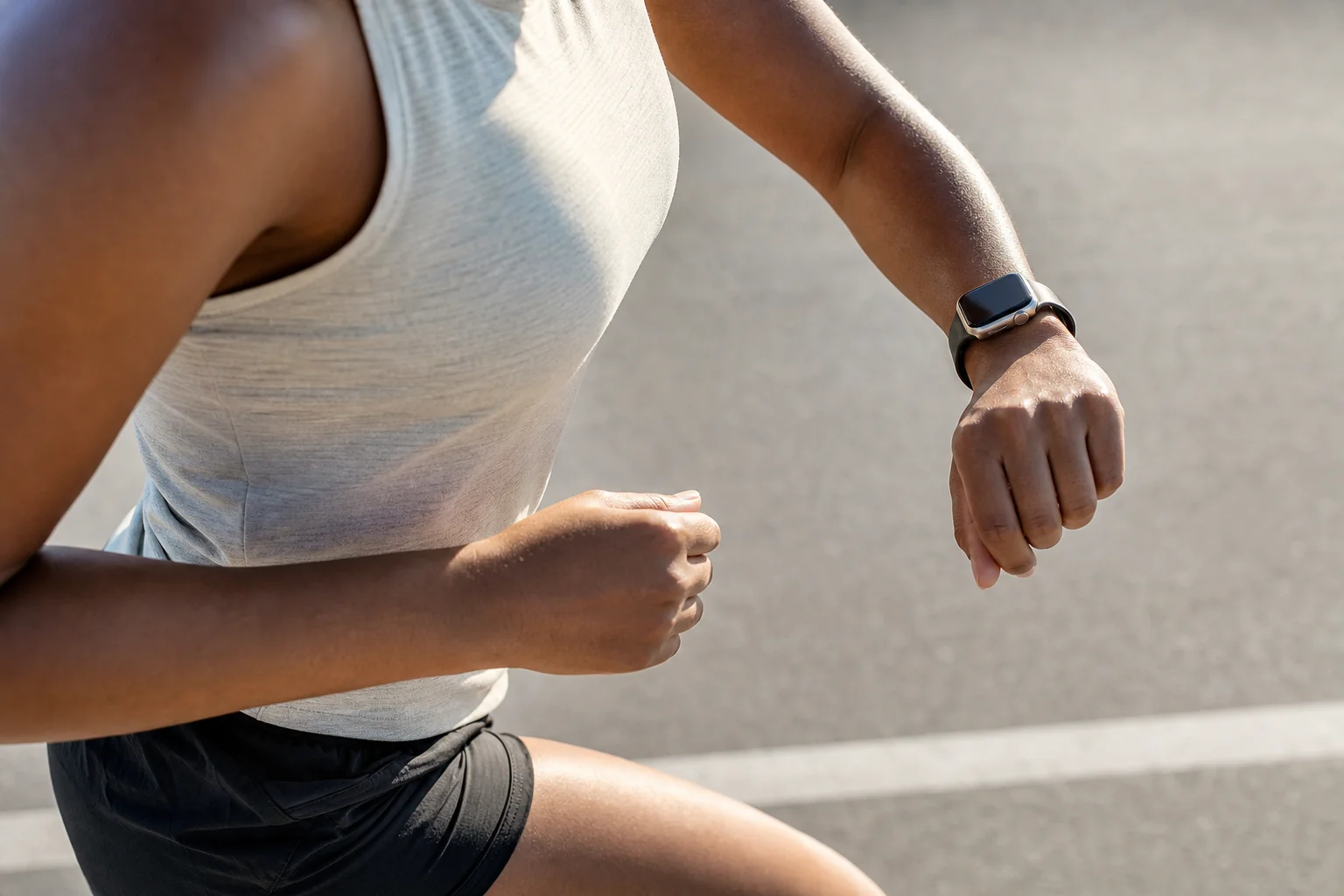 Runner checking smartwatch display during outdoor run on a sunny day