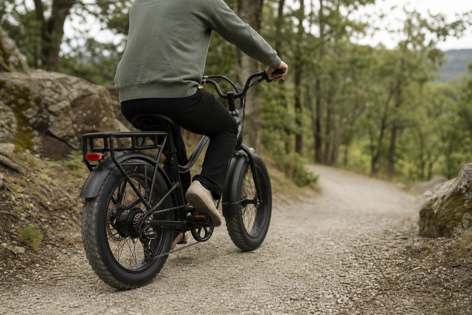 Cyclist navigating gravel path with trees and natural terrain on e-bike