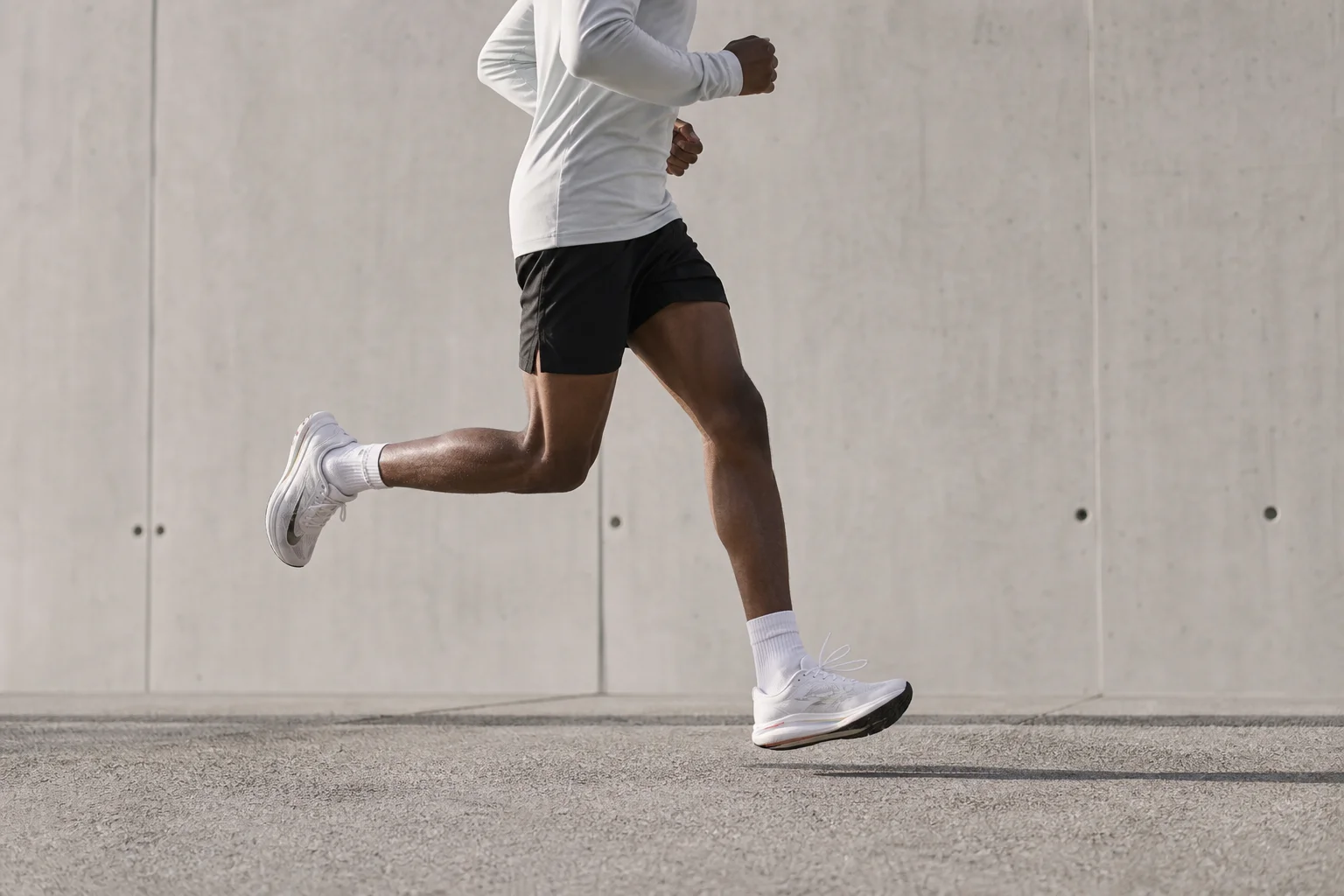 Runner in mid-stride on paved surface showing natural foot strike and posture