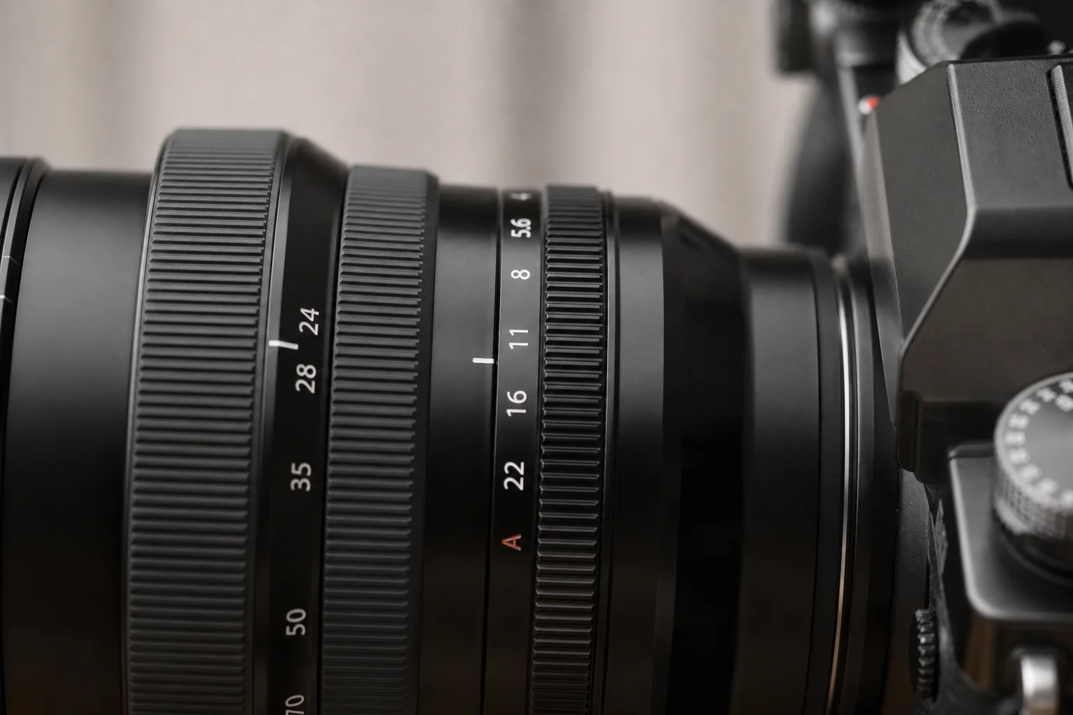 Close-up of camera lens mounted on camera body showing focal length markings