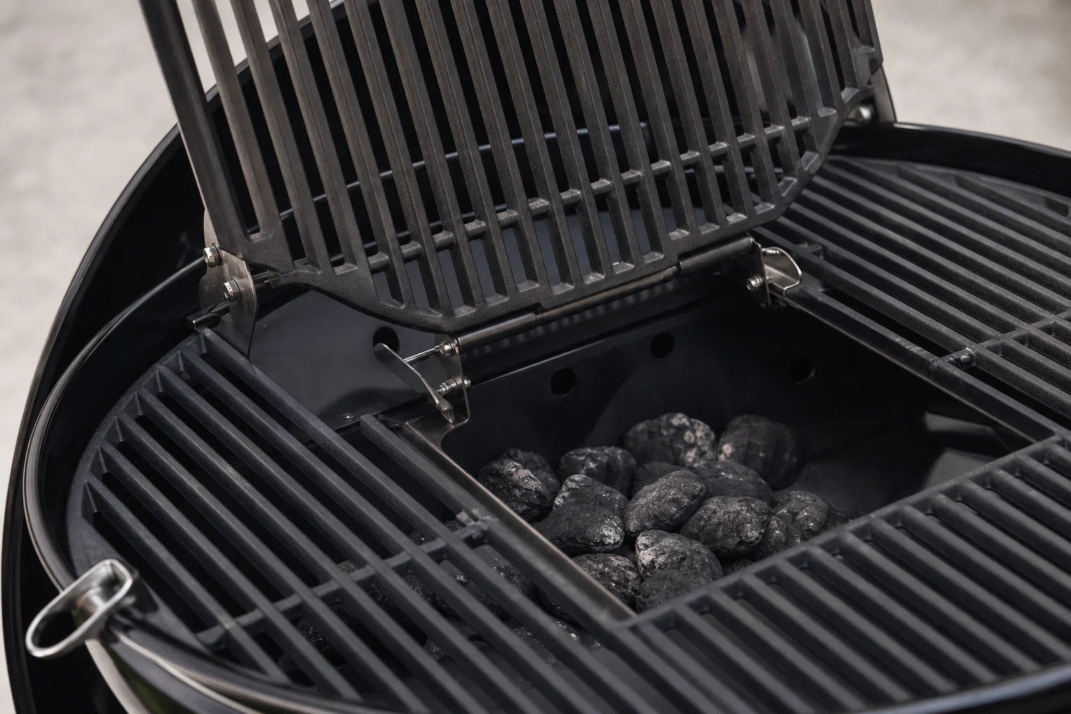 Hinged grill grates on kettle grill with center section open for charcoal access