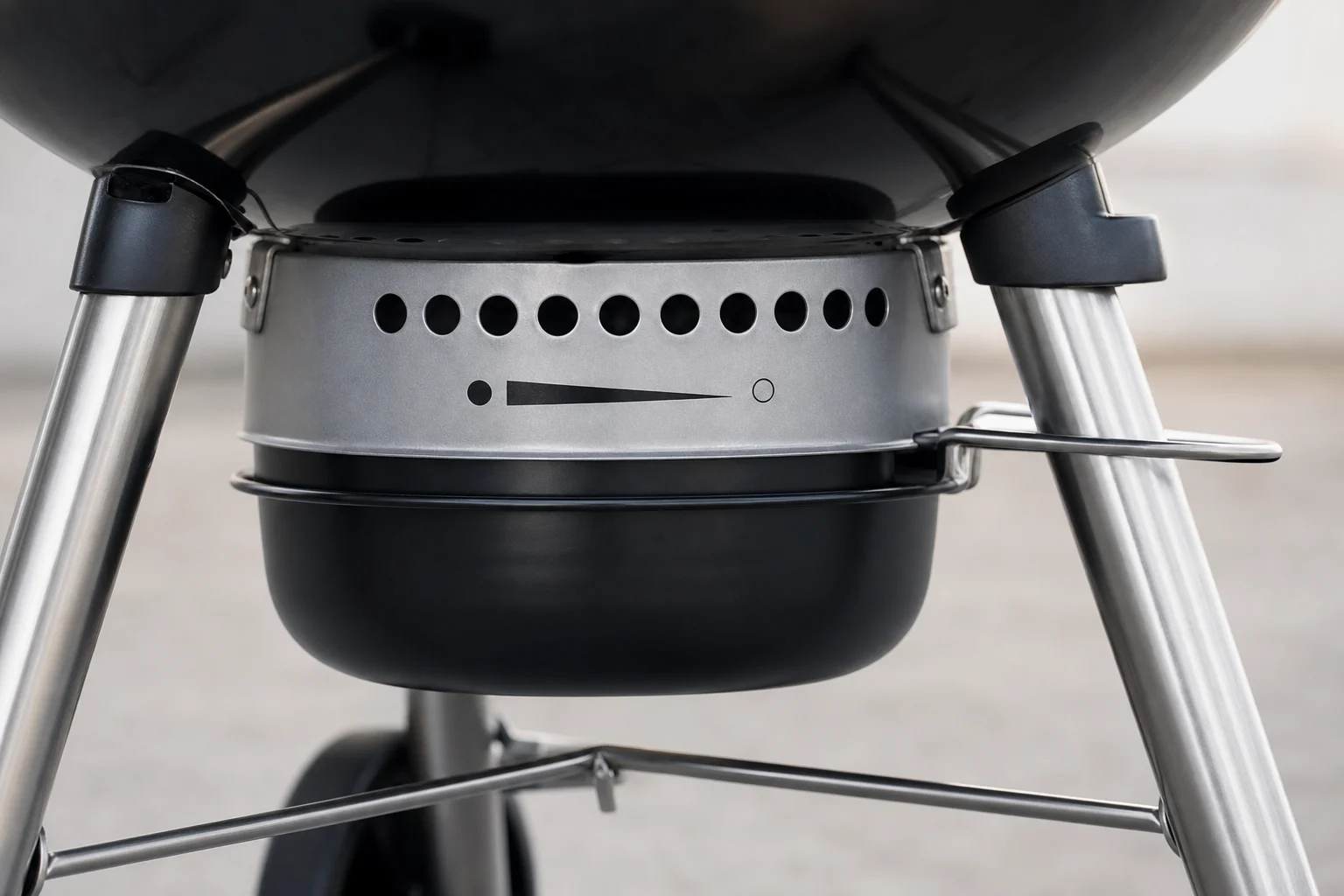 Ash catcher tray beneath kettle grill showing vent position indicators