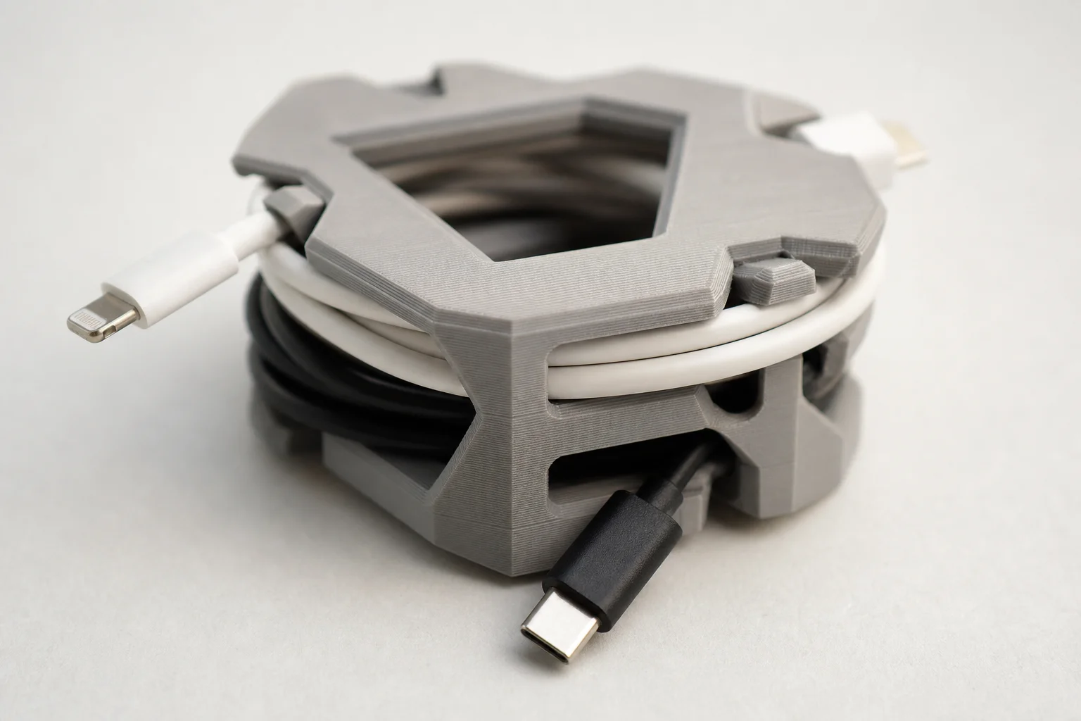 Close-up detail of a 3D printed cable winder holding organized USB and power cables