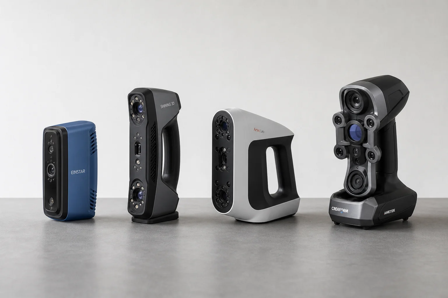 Four 3D scanners arranged on grey surface showing different designs and sizes