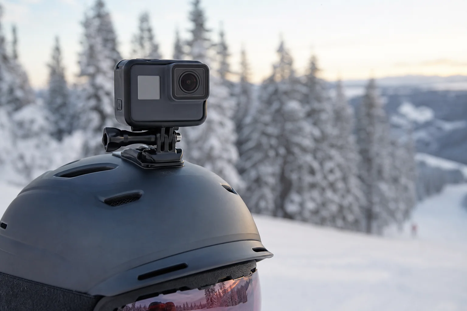 Close-up of action camera mounted on a helmet with snowy landscape behind