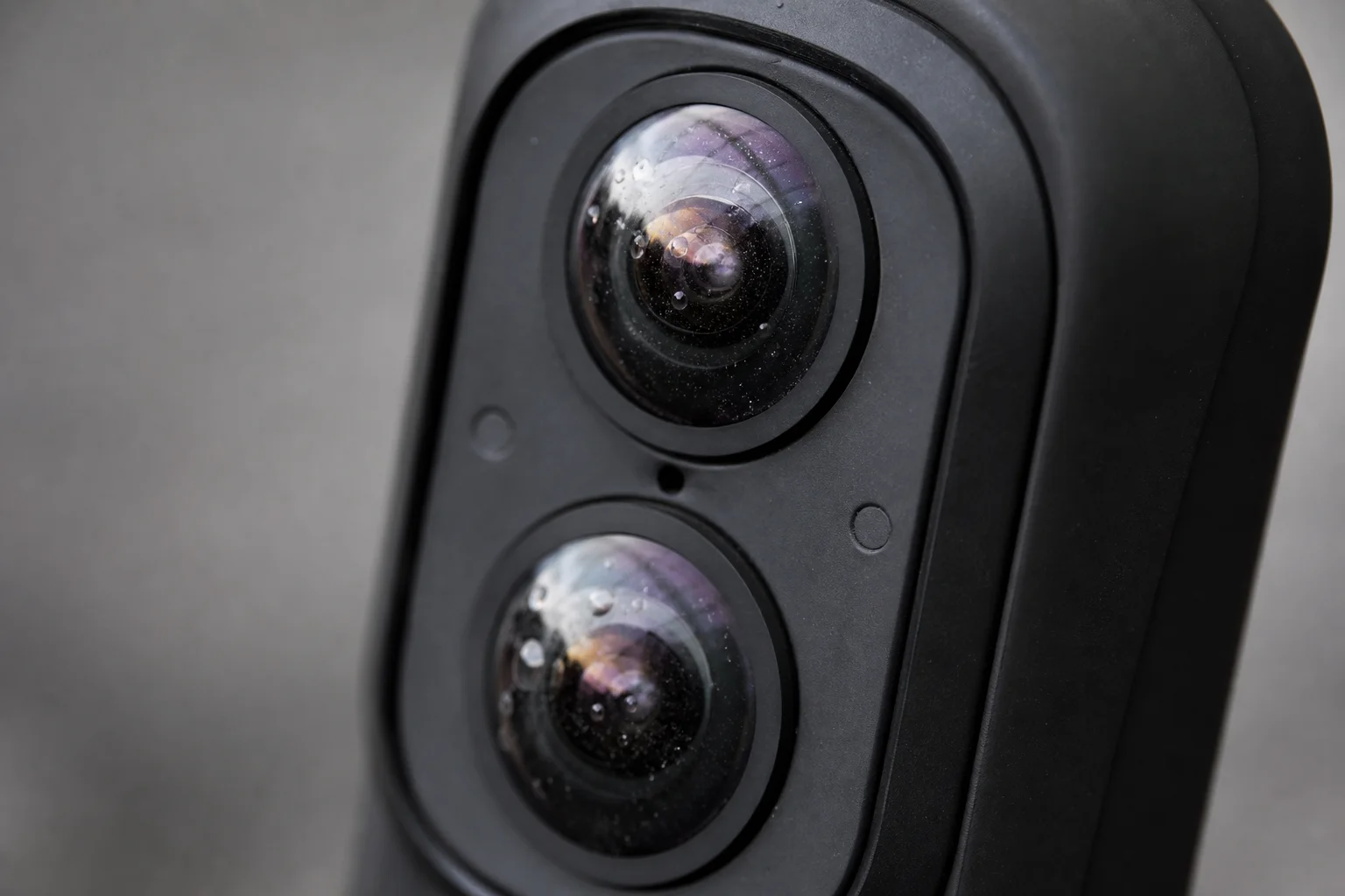 Close-up of dual-lens camera lenses with water droplets and dust