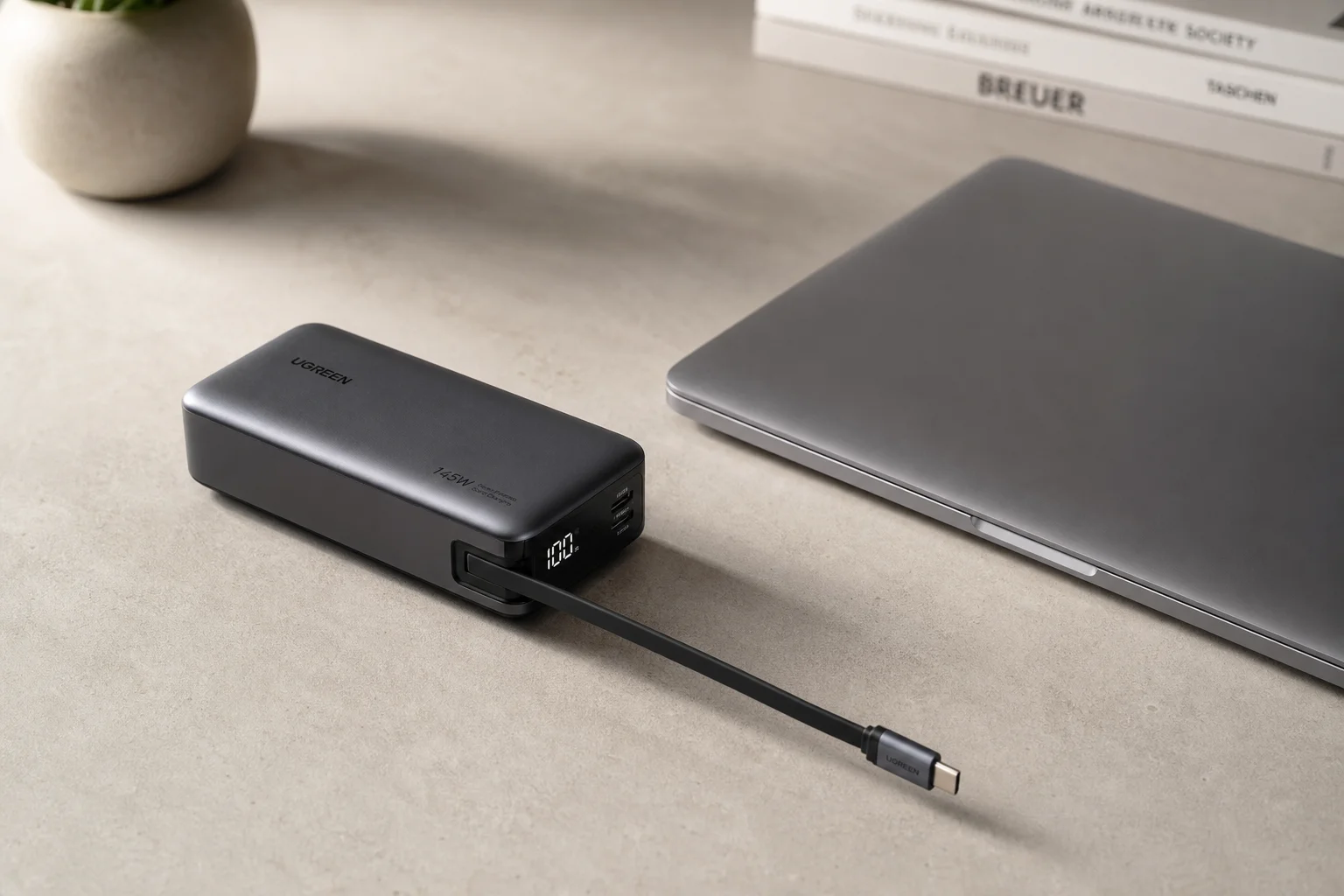 Laptop power bank with extended retractable cable next to laptop