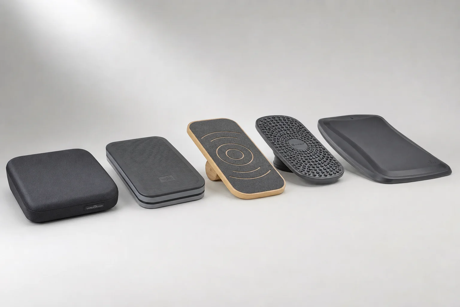 Five anti-fatigue mats and balance boards arranged on grey backdrop