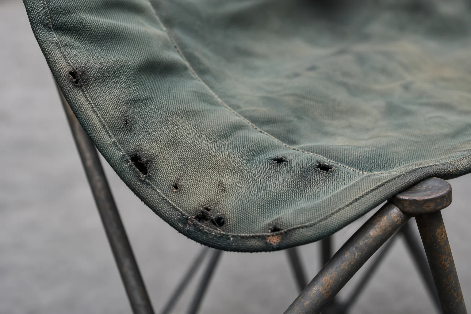 Backpacking chair fabric showing wear and small holes from fire exposure