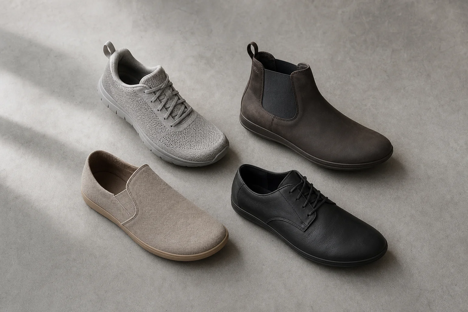 Flat-lay of four different barefoot shoe styles on concrete surface