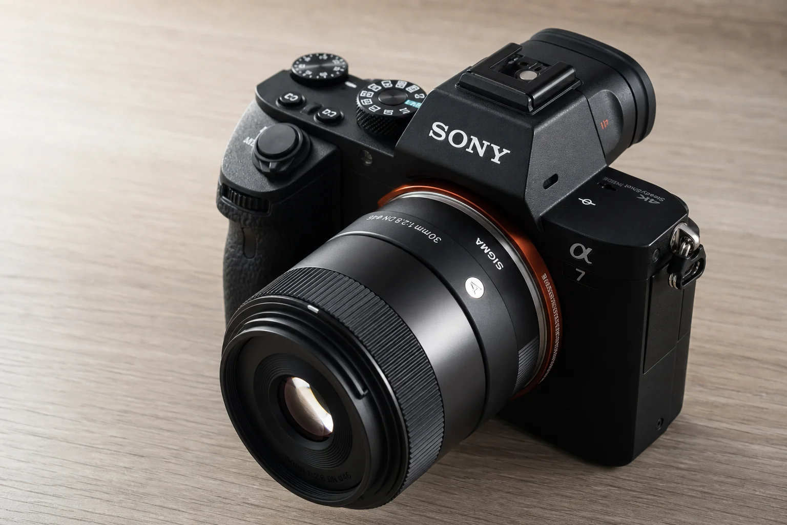 Compact prime lens mounted on a mirrorless camera on wooden desk