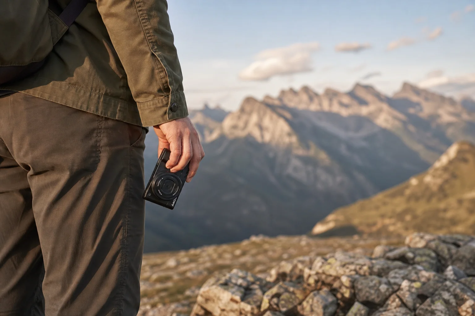 Traveler holding a small compact camera in a mountain landscape
