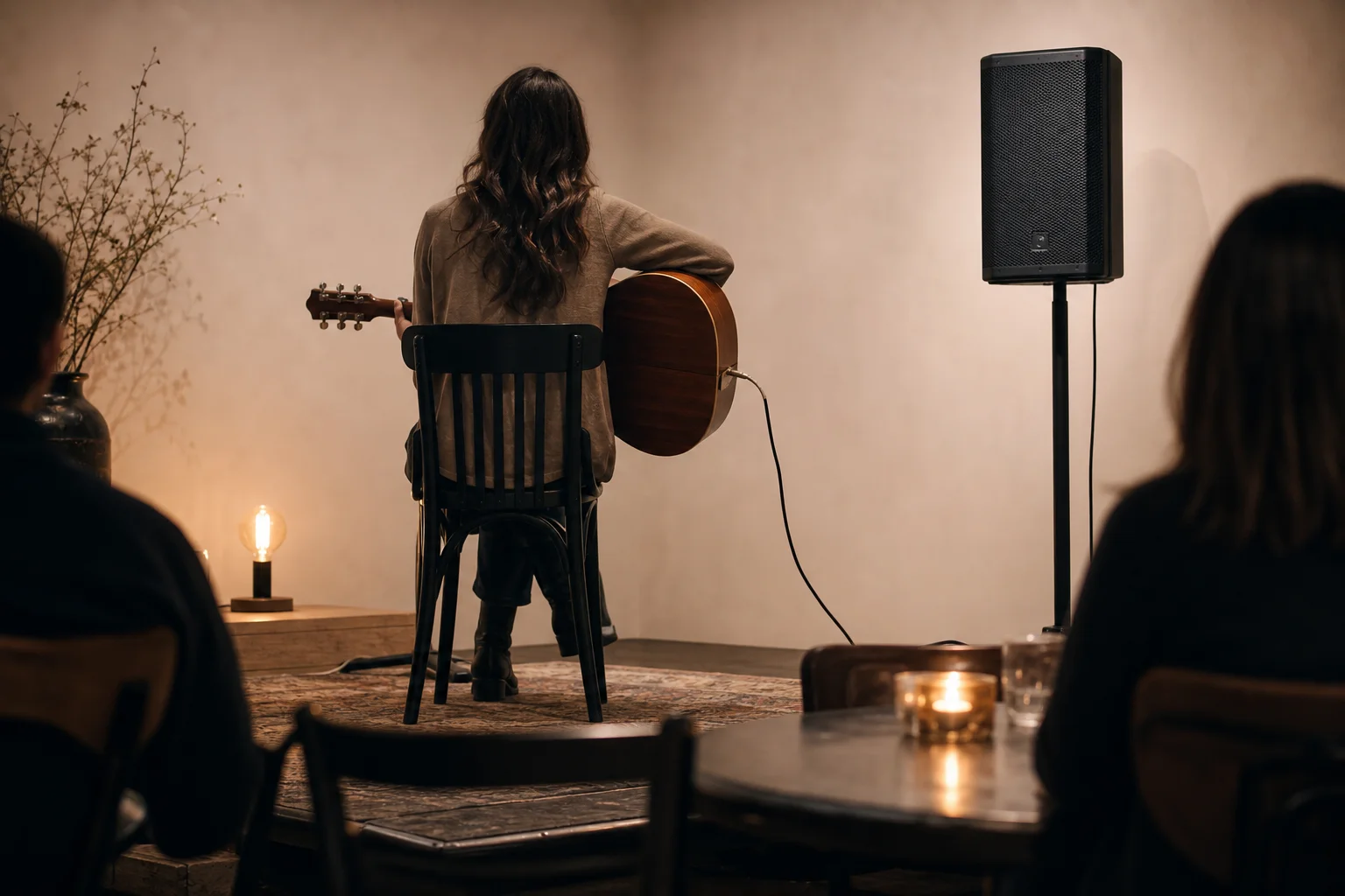 Solo acoustic performer with compact PA speaker on stand in small venue