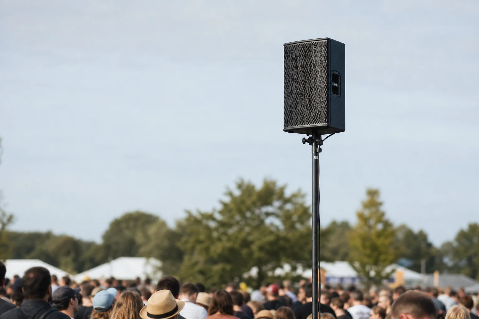 PA speaker mounted on stand elevated above crowd level at outdoor event