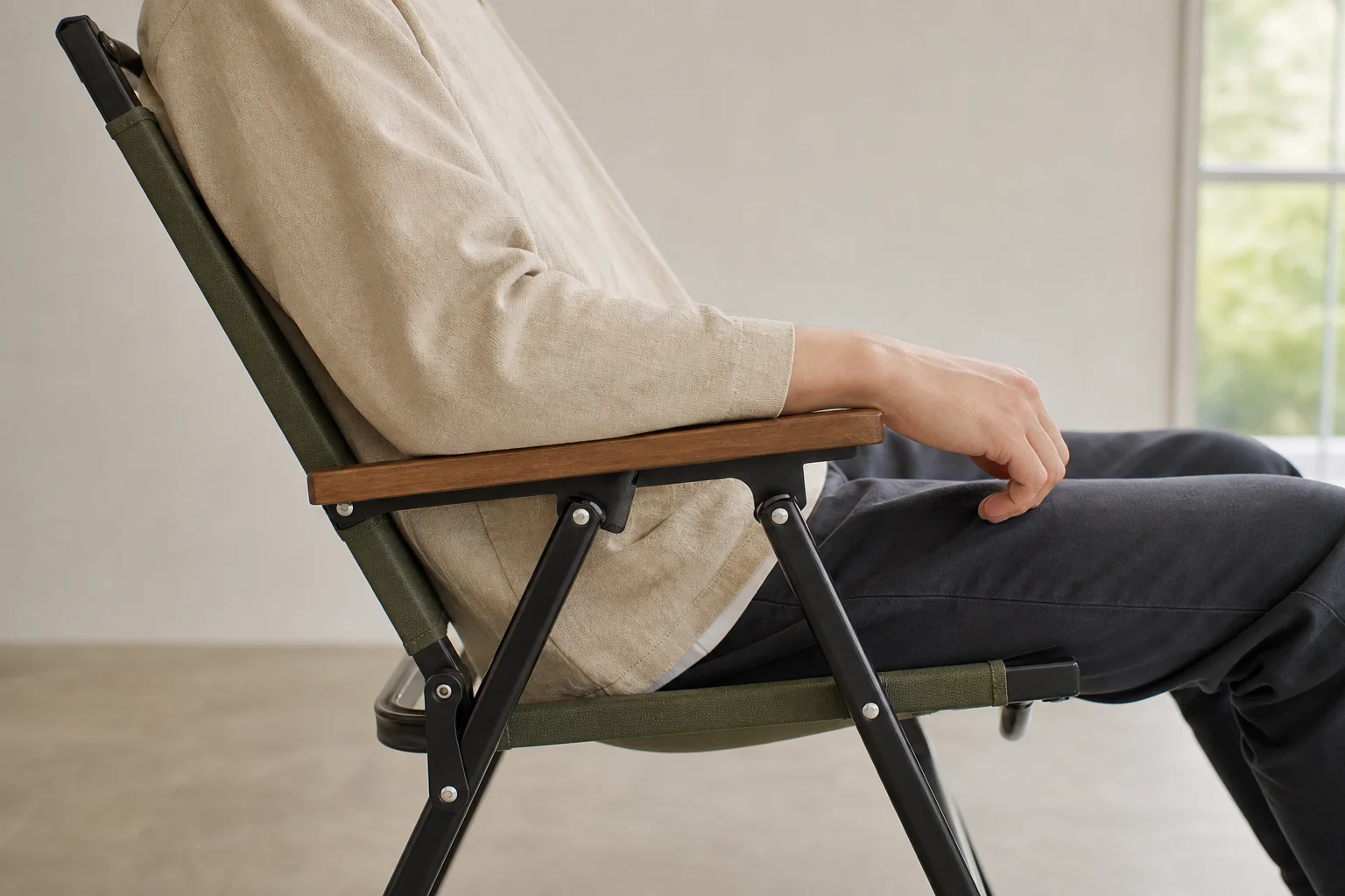 Perfil lateral de una persona sentada en una silla de camping mostrando la ergonomía