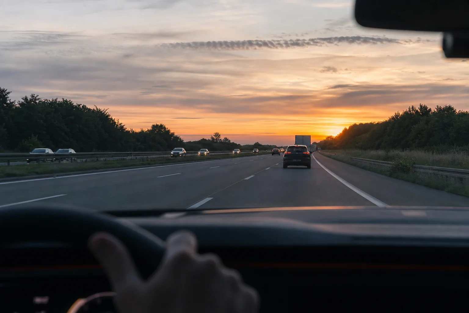 Autopista al atardecer con el salpicadero del vehículo y la carretera por delante