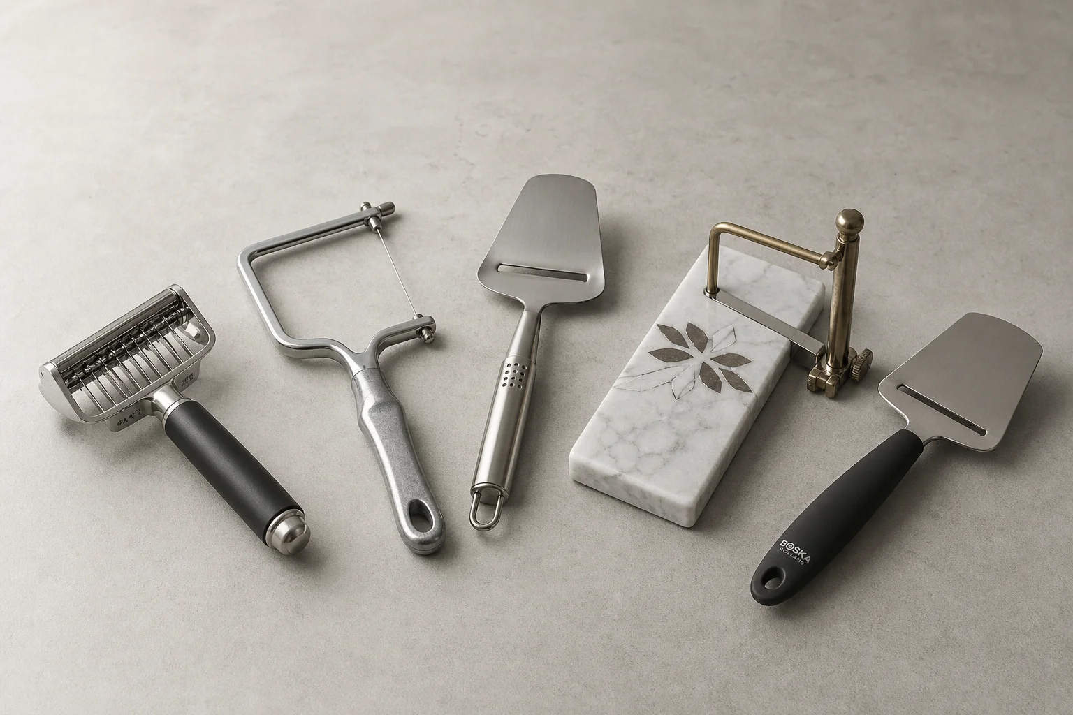 Five different cheese slicers arranged on a concrete surface