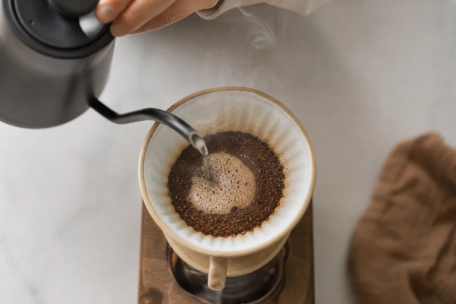 Hands pouring hot water into a pour-over coffee dripper with steam rising