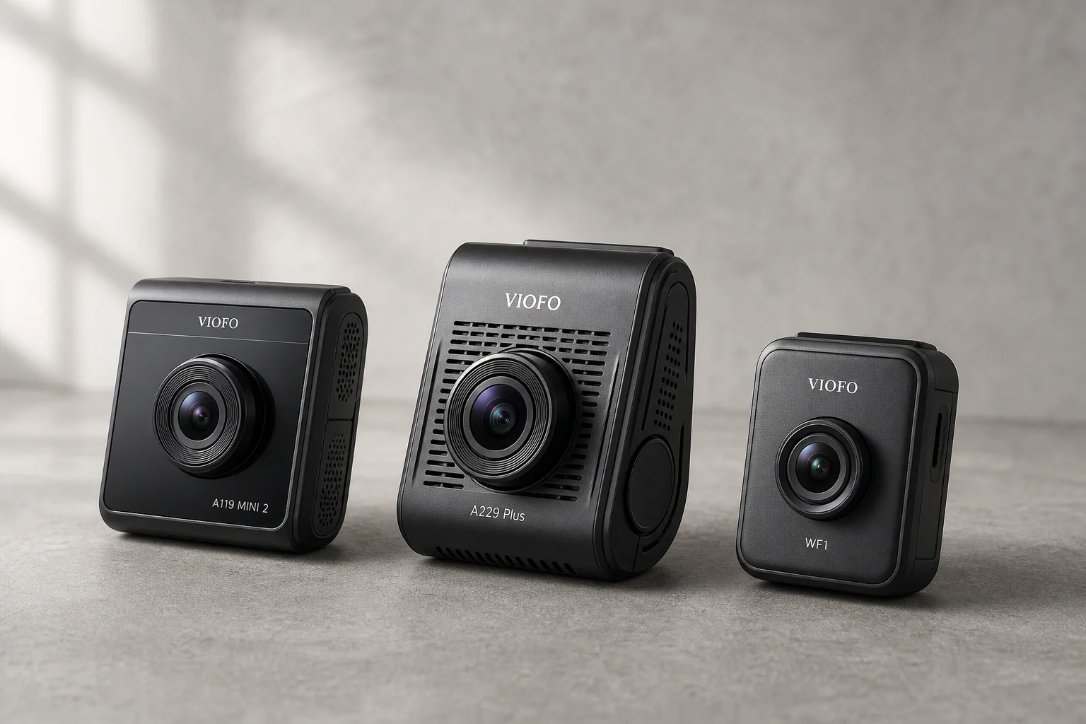 Three VIOFO dash cameras arranged on concrete surface showing size and design differences