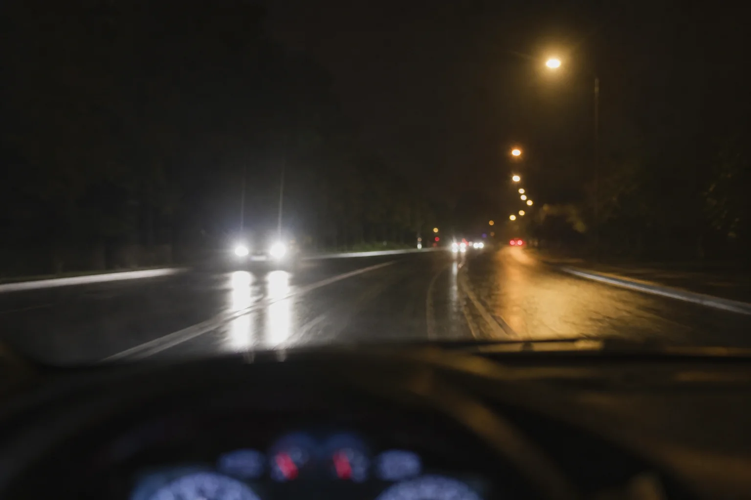 夜間駕駛場景，顯示對向車頭燈與路燈造成的眩光