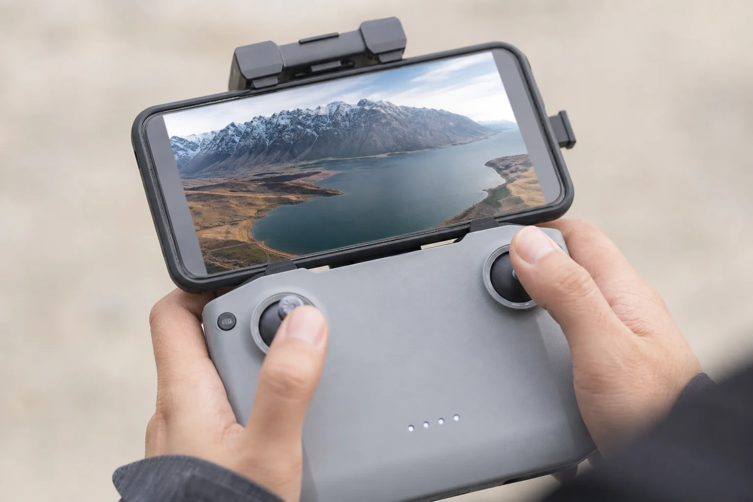 FPV表示用にスマートフォンを装着したコントローラーを持つドローン操縦者