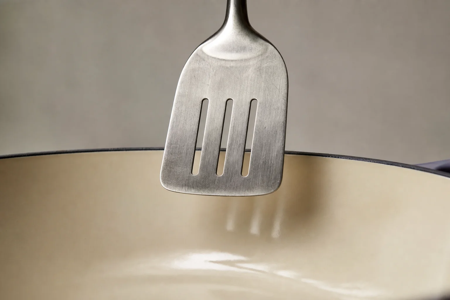 Metal spatula being dropped onto Dutch oven interior for durability testing