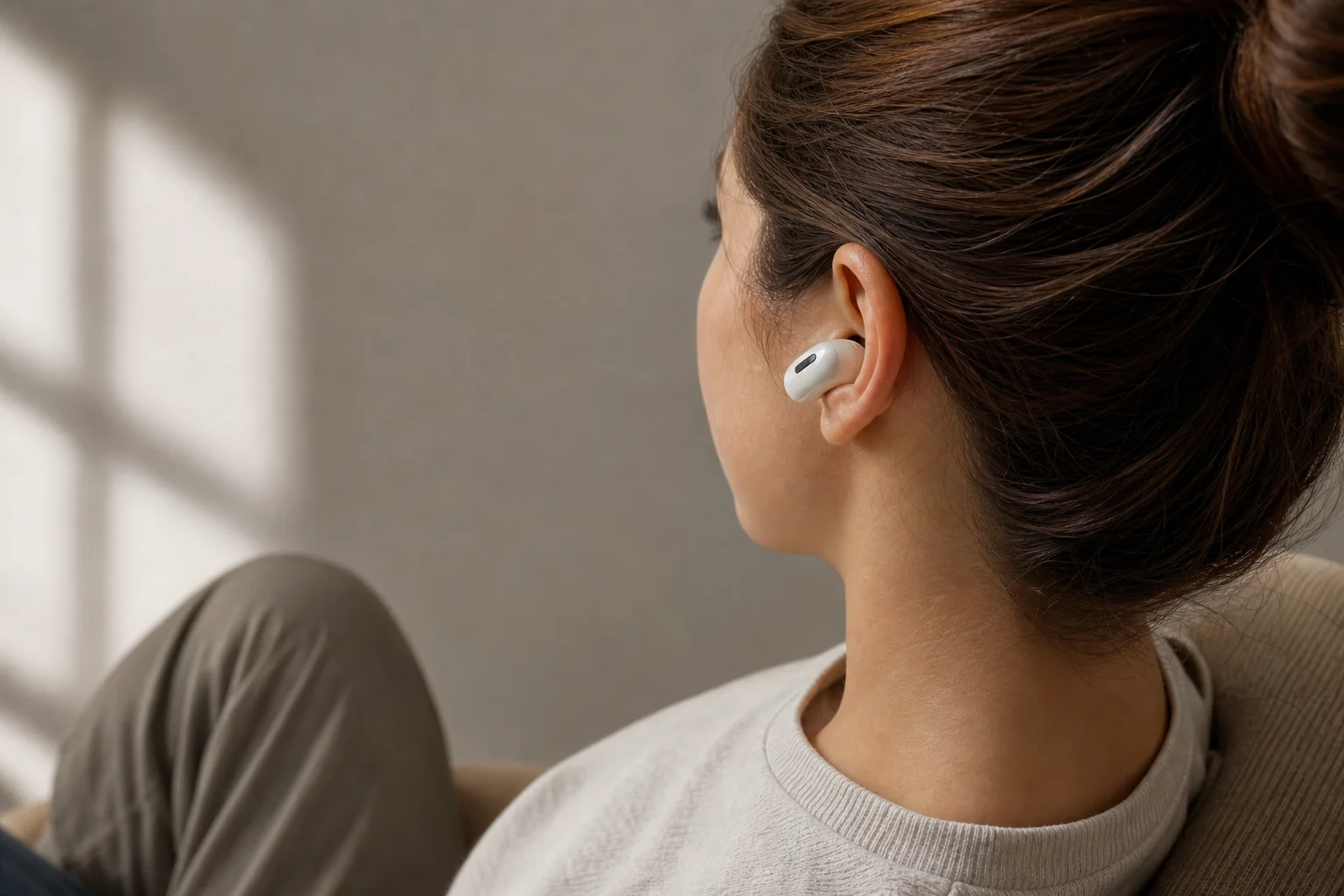 Person wearing earbuds in comfortable seated position indoors