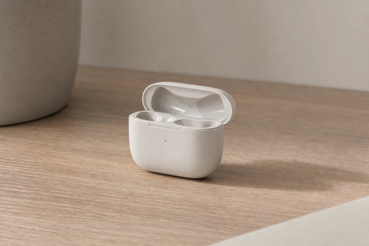 Earbud charging case on wooden desk with soft shadows
