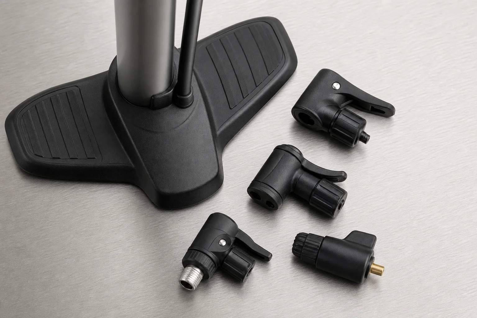 Floor pump with multiple valve head adapters displayed on a work surface
