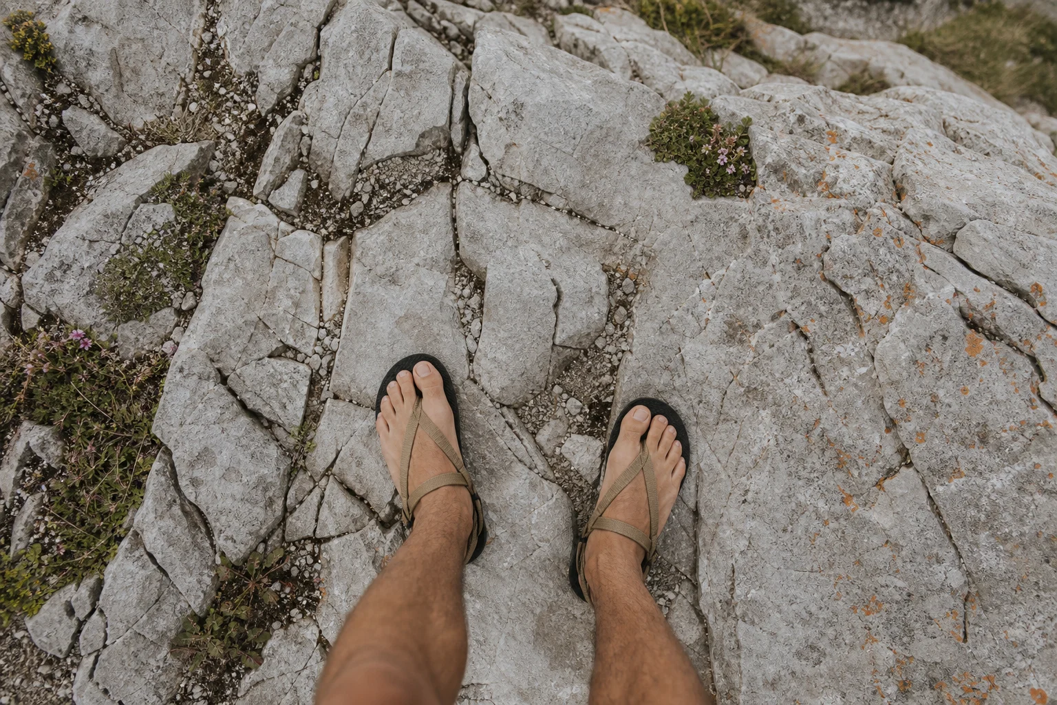 Hiker's feet in minimalist sandals on rough rocky terrain