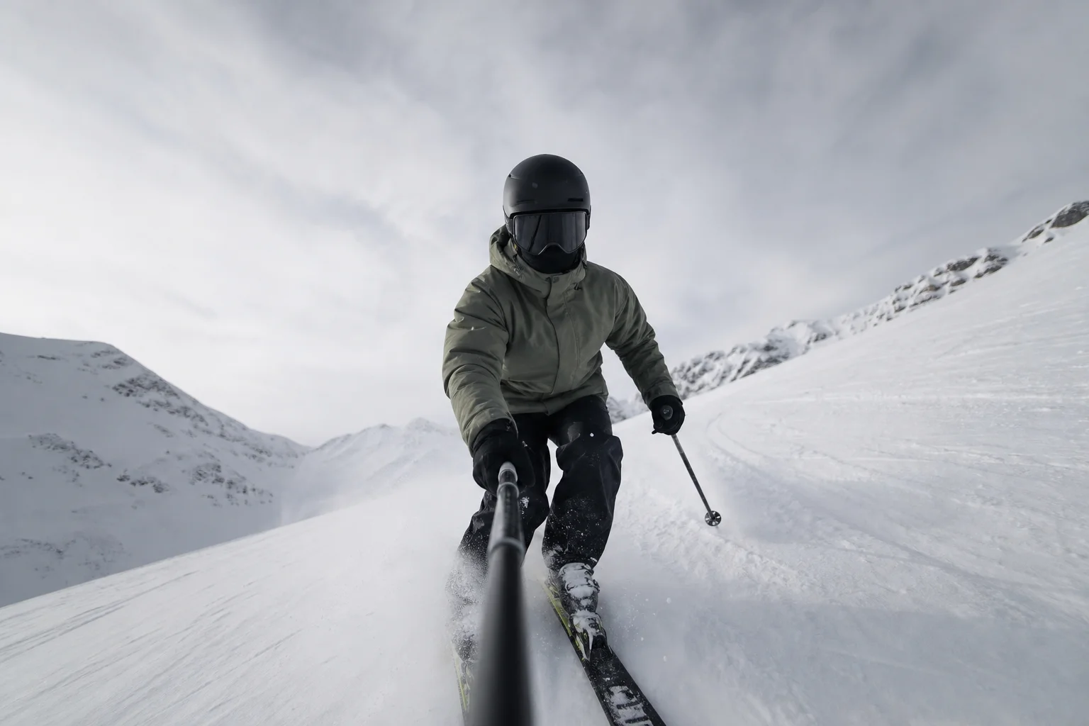 Skier descending snowy slope with camera mounted on ski pole