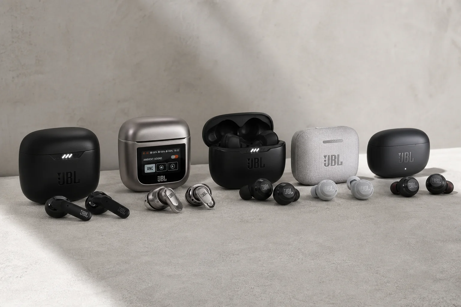 Five JBL earbud models arranged on concrete surface