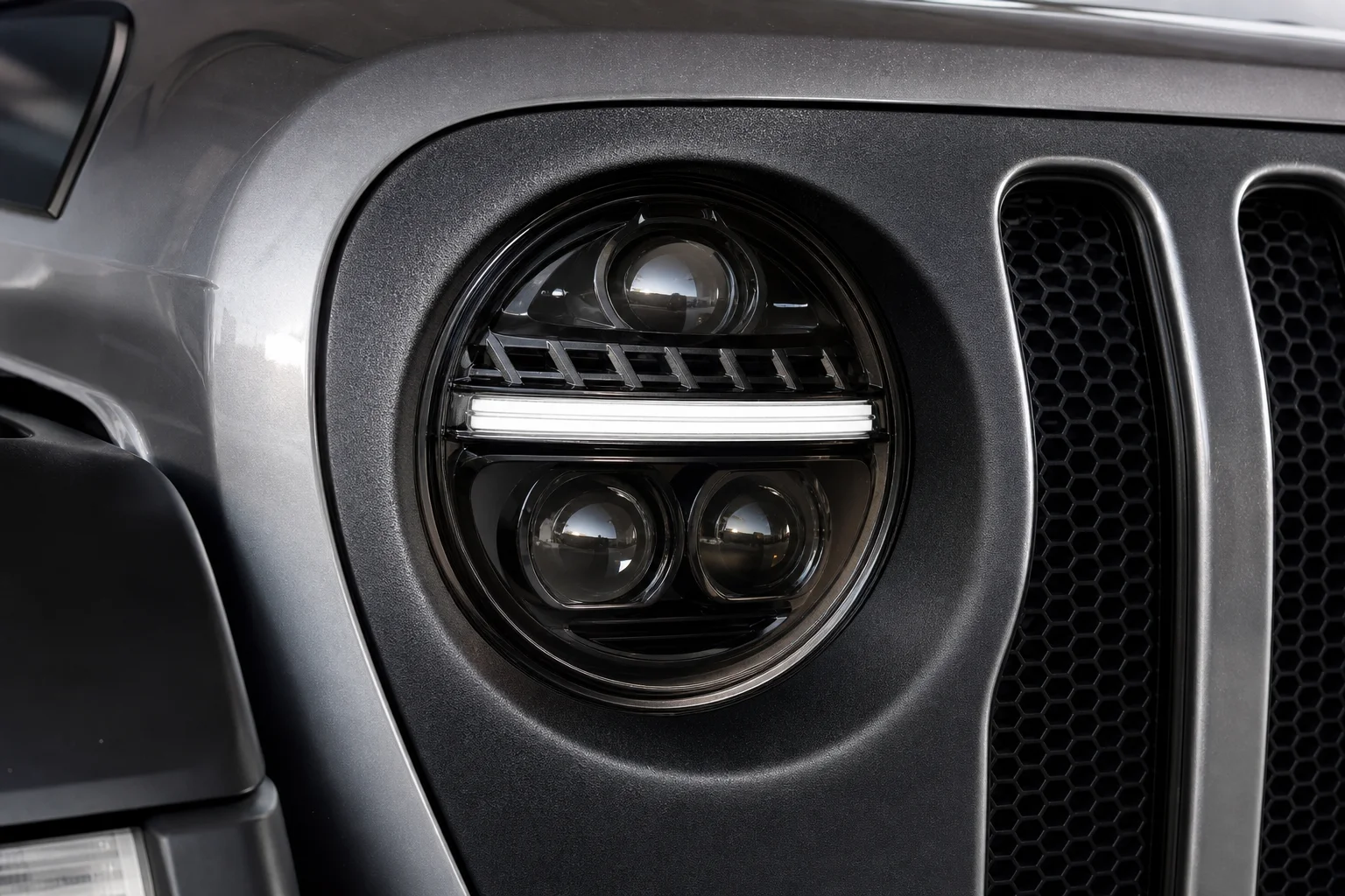 安裝在 Jeep 邊框中的 Truck-Lite 投射式 LED 頭燈，顯示鏡頭細節