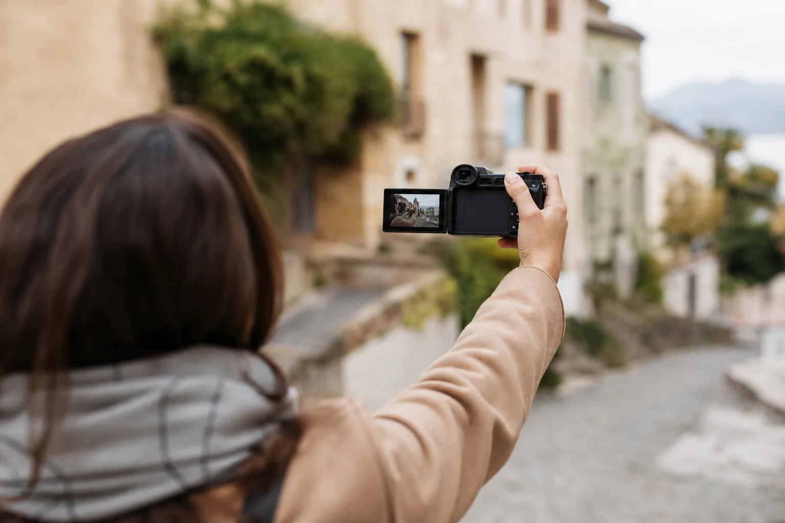 Travel vlogger filming outdoors with flip-out camera screen on scenic street