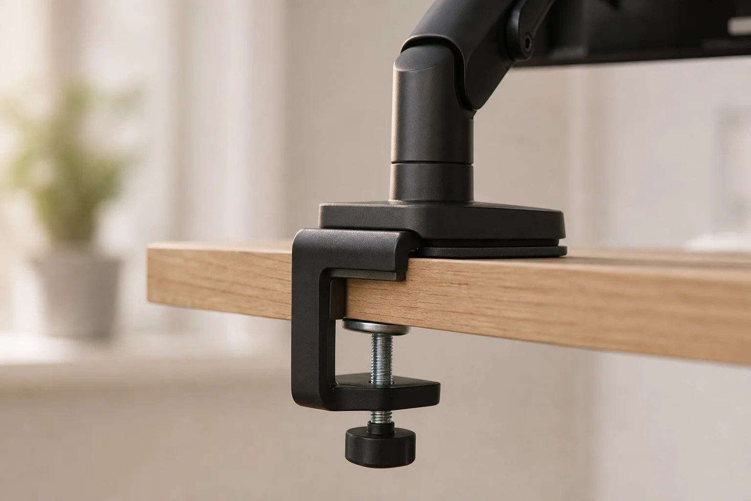 Close-up of monitor arm clamp mechanism with rubber padding on desk