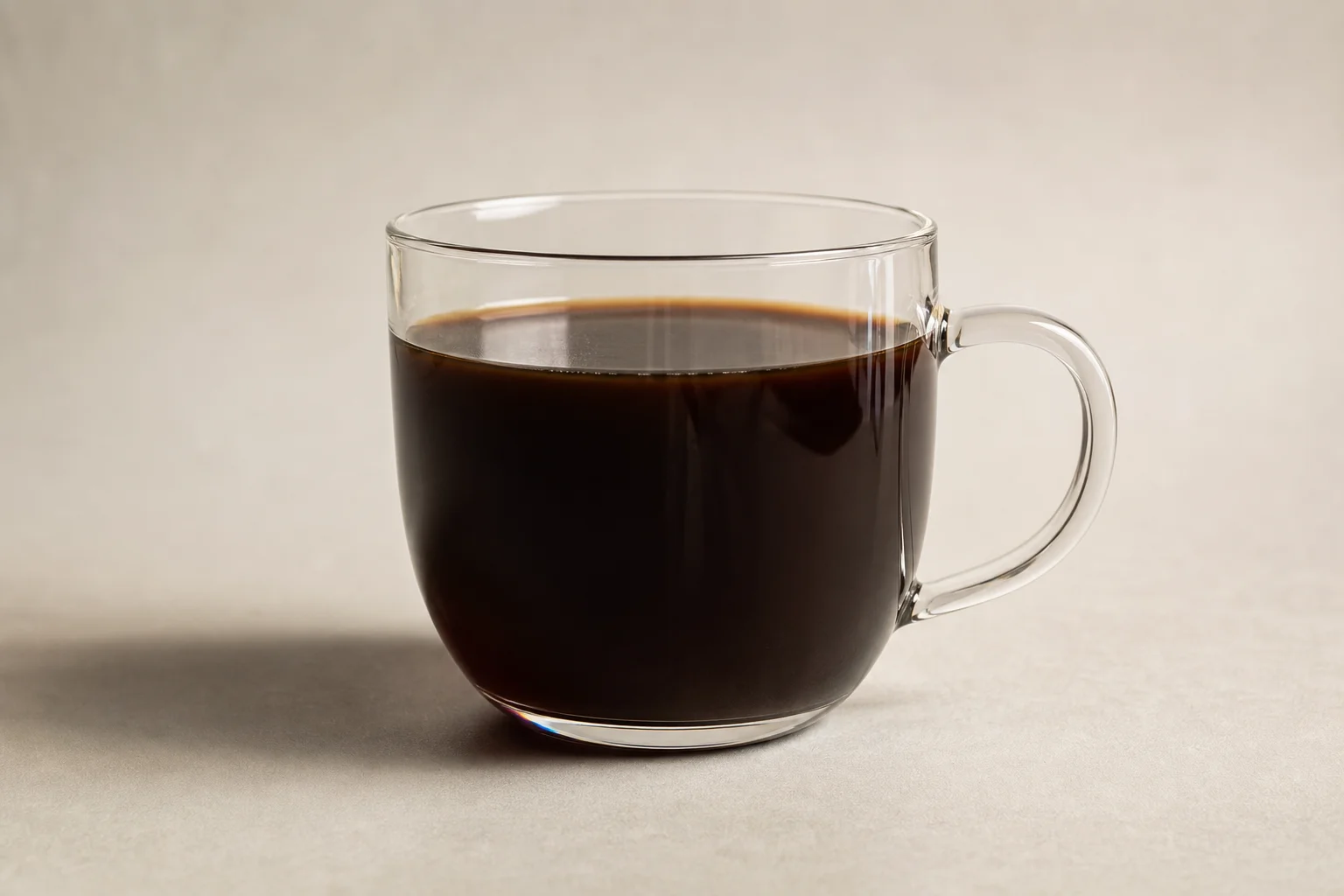 Transparent glass mug displaying rich dark coffee with natural light