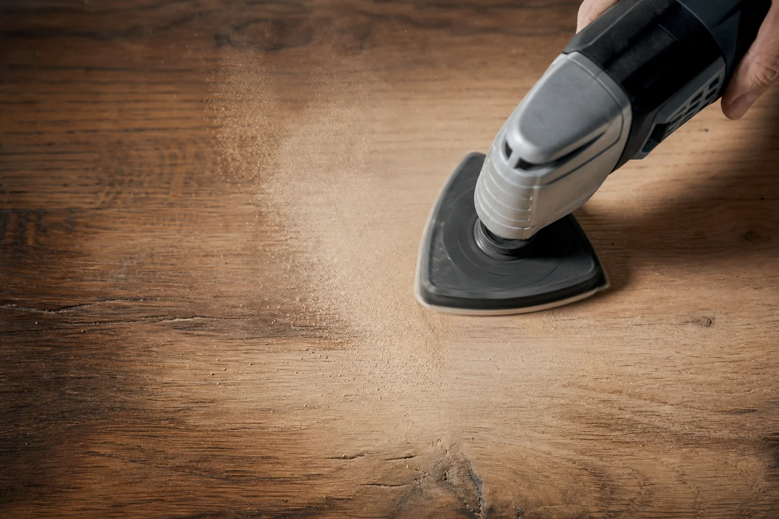Oscillating multi-tool sanding pad smoothing a wooden surface
