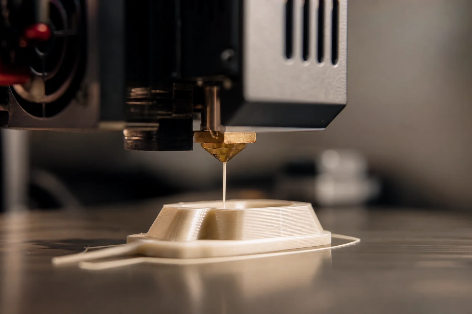 Gros plan sur une buse d'imprimante 3D extrudant du filament sur le plateau d'impression