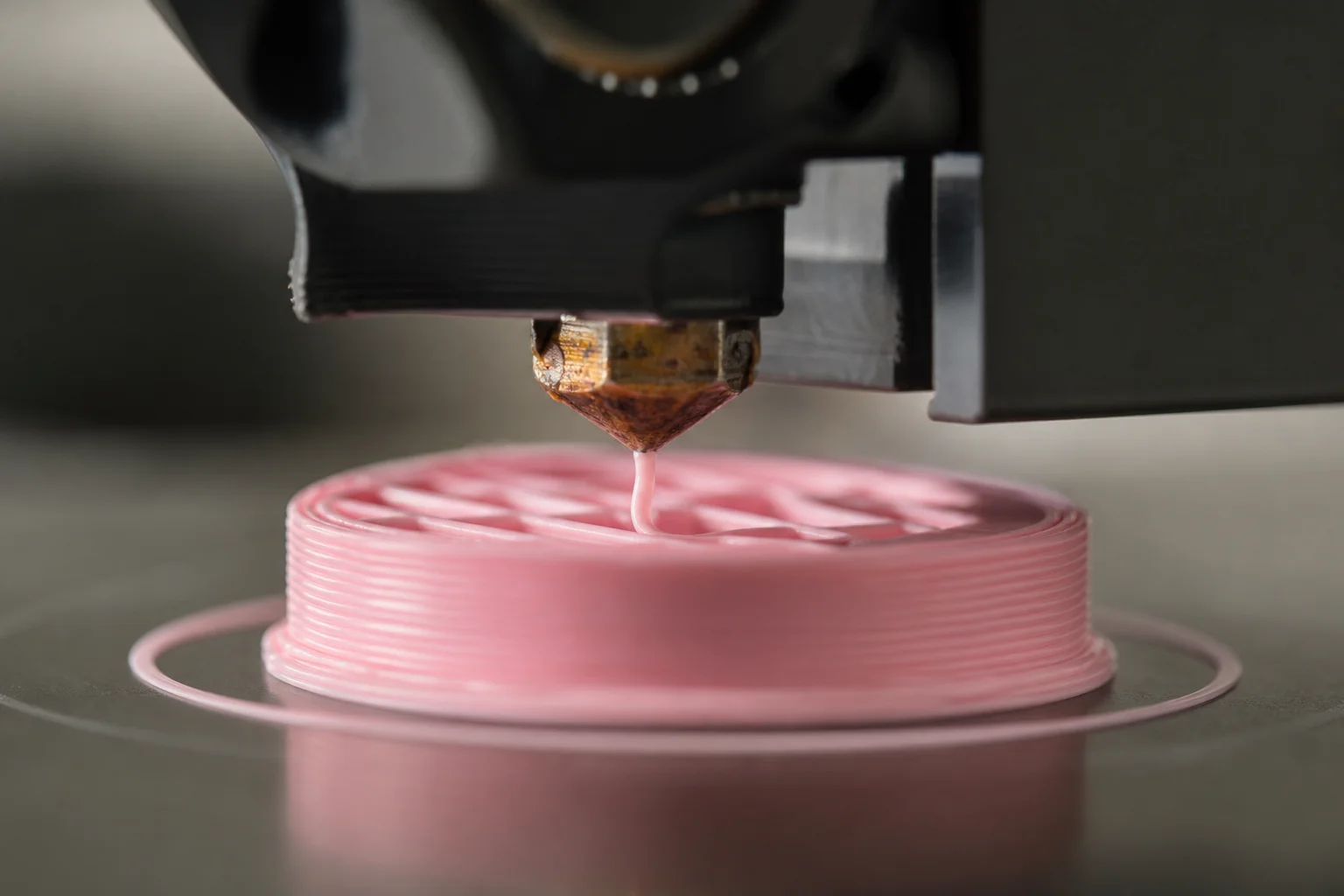 3D-Druckerdüse extrudiert pinkes Filament auf ein beheiztes Druckbett
