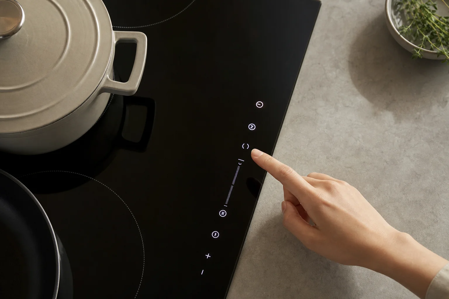 Hand adjusting touch controls on a modern induction cooktop display