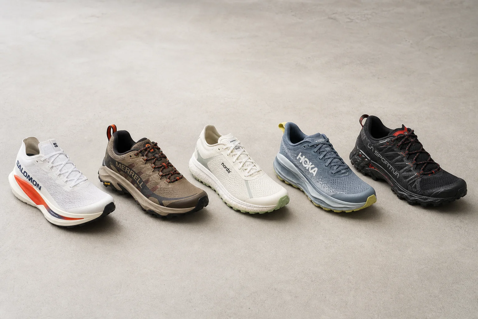 Five trail running shoes arranged on concrete surface representing different styles and purposes