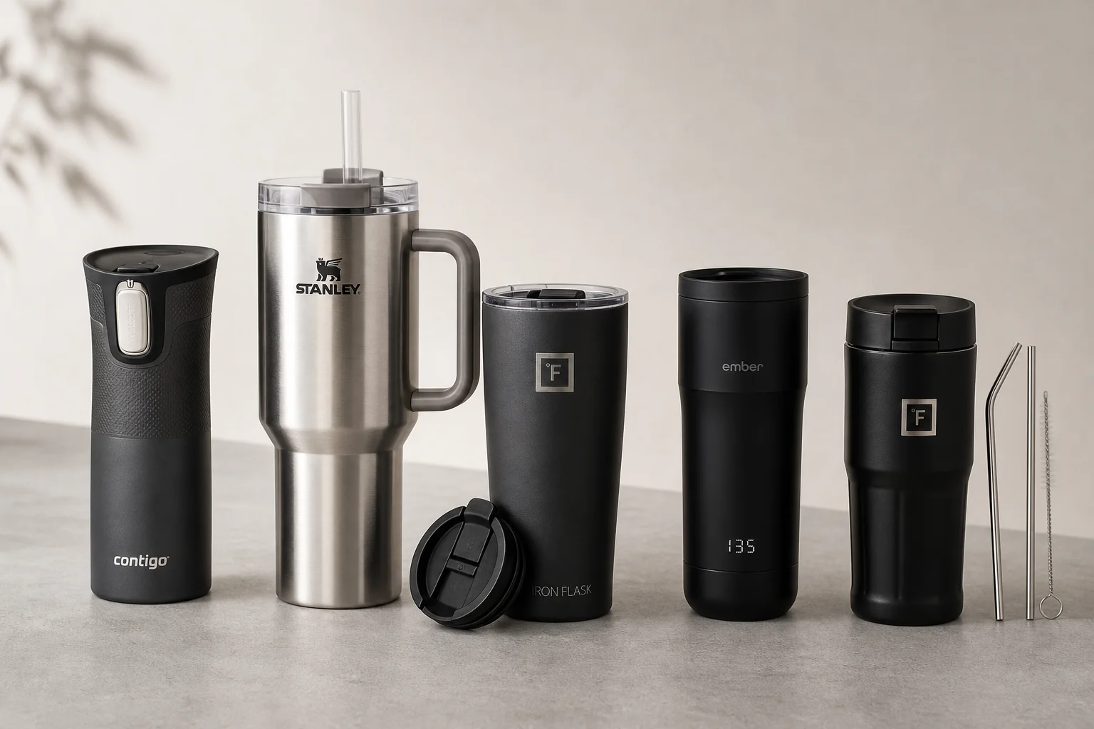 Five travel mugs arranged in ranking order on a concrete surface
