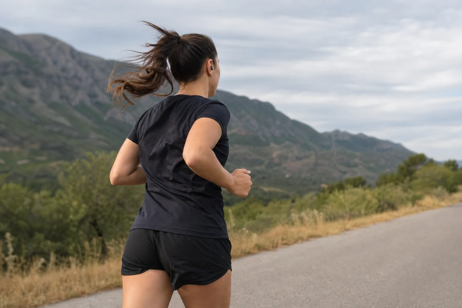 Runner wearing earbuds during outdoor workout in natural daylight