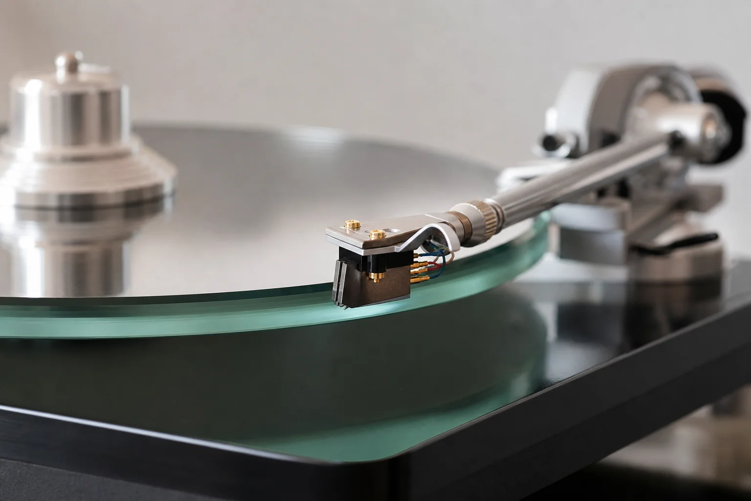 Close-up of glass platter and aluminum tone arm with cartridge detail