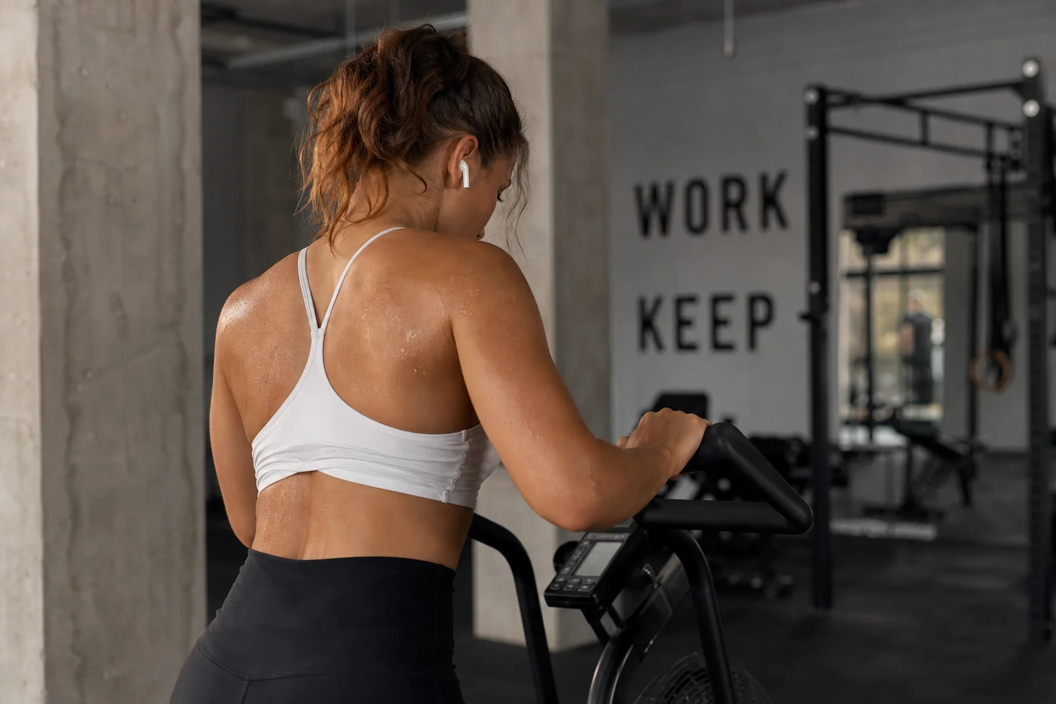 Person using earbuds during a workout session in a gym