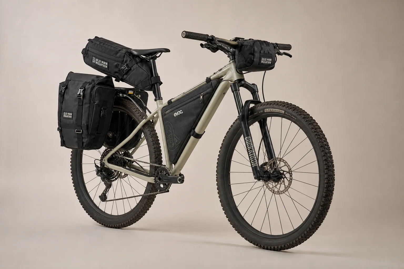 Fully loaded trail bike with Old Man Mountain racks and bags on neutral backdrop