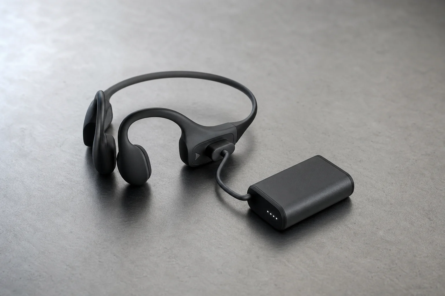 Suunto Wing headphones with portable charging bank on outdoor surface