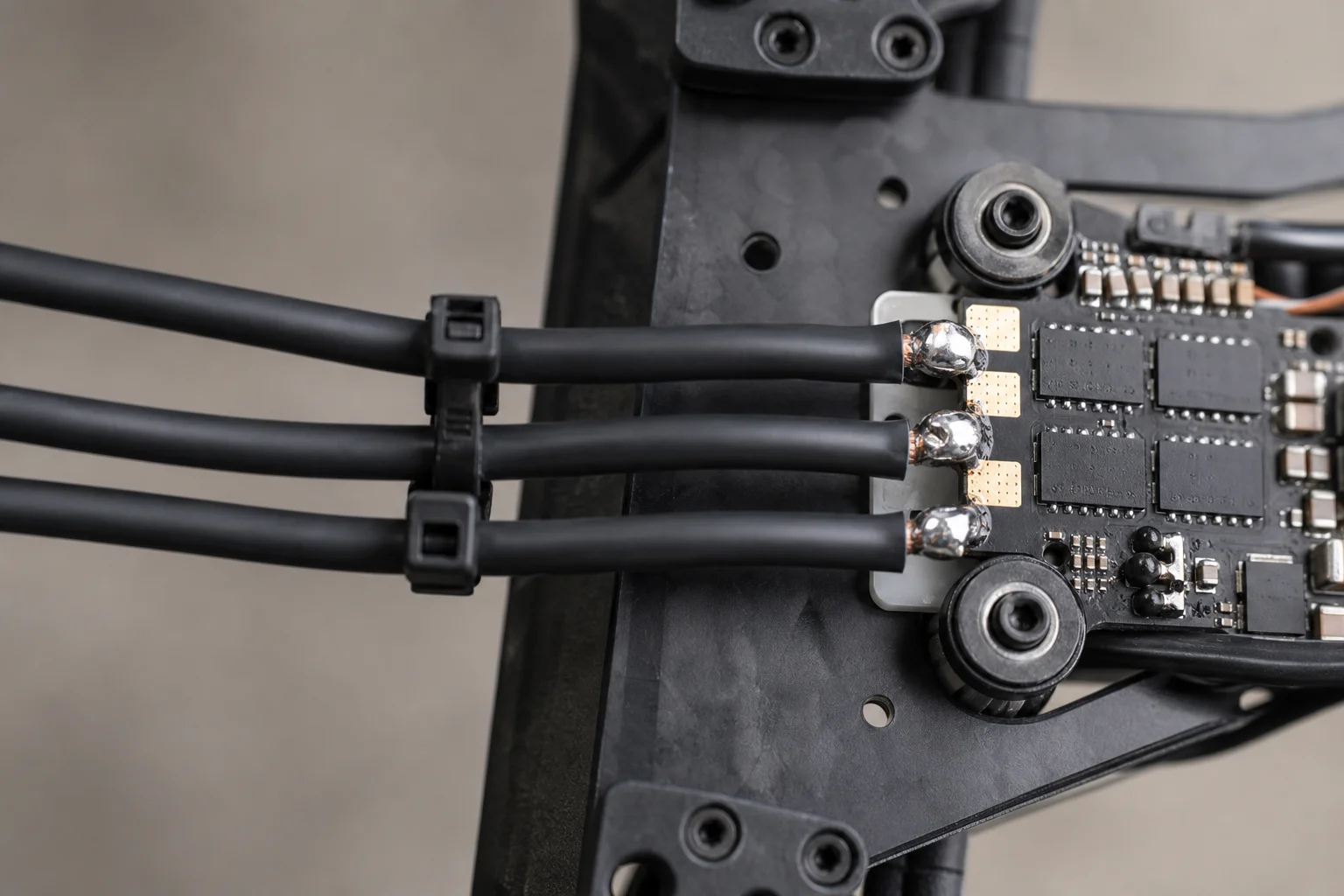 Motor wires soldered to ESC pads and secured with zip ties on arm