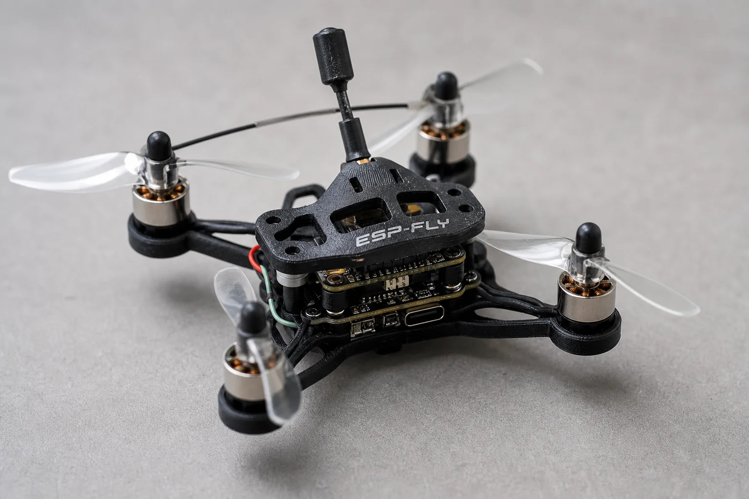 組裝完成的 ESP-FLY 微型無人機放置在灰色表面上，展示其精巧的四軸飛行器設計