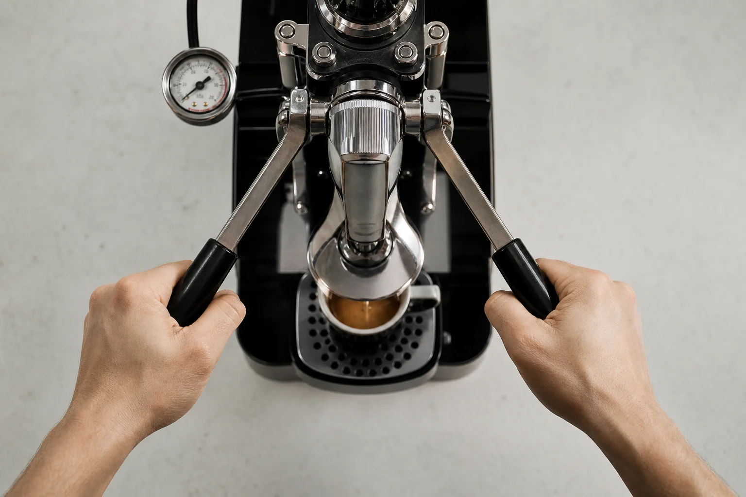 Hands operating the lever arms of a manual espresso machine with pressure gauge visible